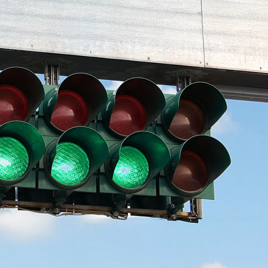 A horizontally aligned traffic light with several red and green lights switches to green