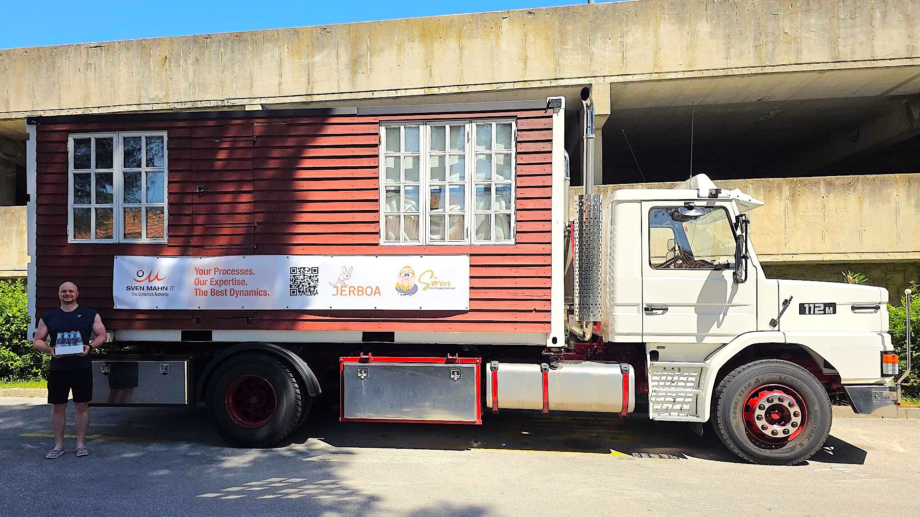 Der Truck von Sven Mahn IT steht im Umfeld der Dynamics Minds. Zu sehen ist ein Werbebanner am Truck und ein Mitarbeiter, der einen Kasten Jerboa-Getränke trägt.
